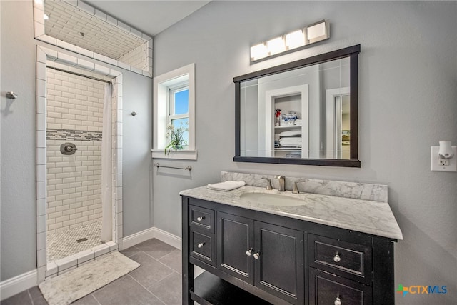 bathroom with tile patterned flooring, vanity, and a tile shower