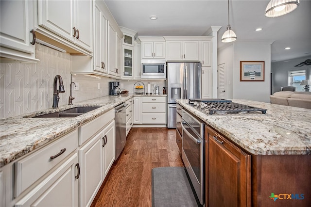 kitchen with stainless steel appliances, white cabinets, dark hardwood / wood-style floors, light stone countertops, and pendant lighting