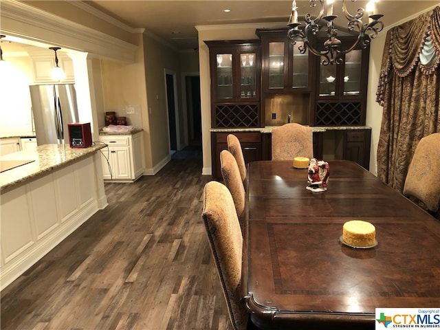 wine area featuring dark hardwood / wood-style flooring, crown molding, and an inviting chandelier