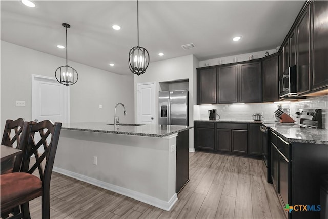 7005 Mcgregor Loop, Killeen, TX 76549 - kitchen featuring stainless steel appliances, light wood finished floors, dark stone counters, a chandelier, and recessed lighting