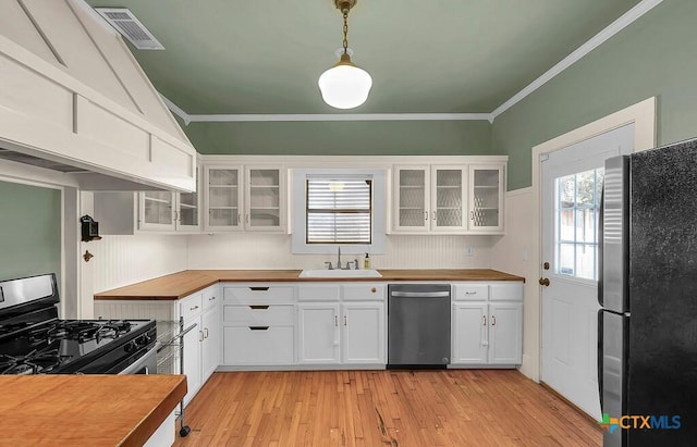 905 N 33rd St, Waco, TX 76707 - kitchen with stainless steel appliances, butcher block countertops, white cabinetry, light wood-style floors, and ornamental molding