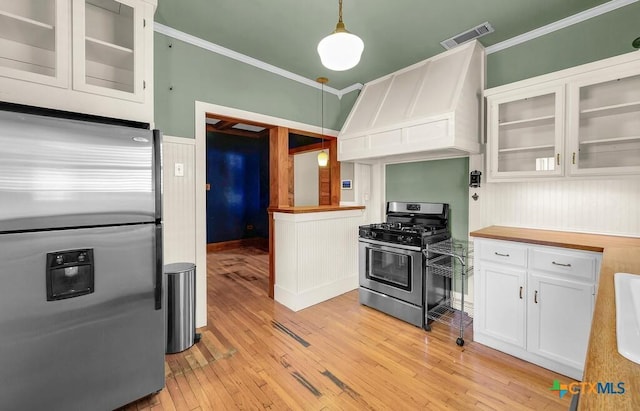 905 N 33rd St, Waco, TX 76707 - kitchen with stainless steel appliances, premium range hood, crown molding, white cabinetry, and butcher block counters