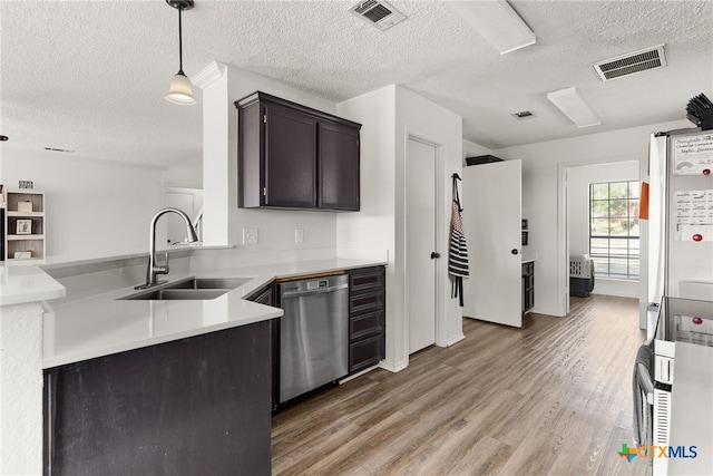 kitchen with stainless steel dishwasher, a textured ceiling, sink, wood-type flooring, and decorative light fixtures