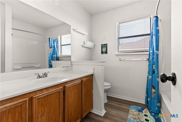 full bathroom with hardwood / wood-style floors, vanity, toilet, and shower / tub combo with curtain