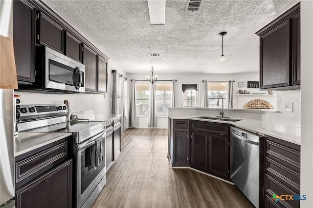 kitchen featuring appliances with stainless steel finishes, dark hardwood / wood-style flooring, a textured ceiling, sink, and pendant lighting