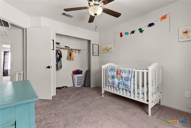 bedroom with ceiling fan, a closet, carpet floors, and a nursery area