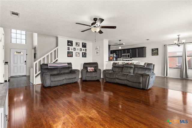 living room with a textured ceiling, ceiling fan with notable chandelier, a healthy amount of sunlight, and dark hardwood / wood-style floors