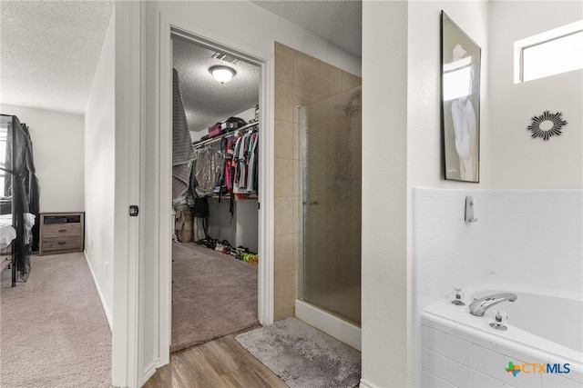 bathroom with separate shower and tub, hardwood / wood-style floors, and a textured ceiling