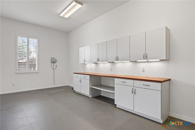 2206 Pheasant Run Ln, Temple, TX 76502 - kitchen featuring wood counters, concrete flooring, built in study area, and white cabinets