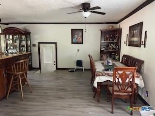304 Oak Plz, Austin, TX 78753 - dining room with ceiling fan, wood finished floors, crown molding, a dry bar, and a textured ceiling