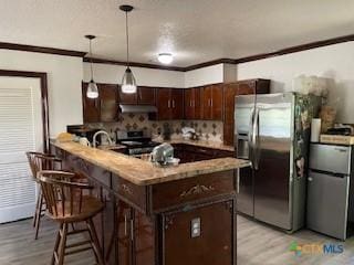 304 Oak Plz, Austin, TX 78753 - kitchen with stainless steel appliances, dark brown cabinets, crown molding, under cabinet range hood, and a peninsula