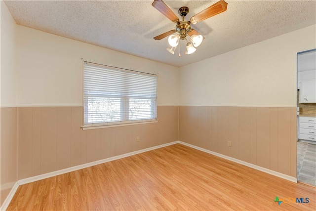 unfurnished room featuring light hardwood / wood-style floors, a textured ceiling, and ceiling fan