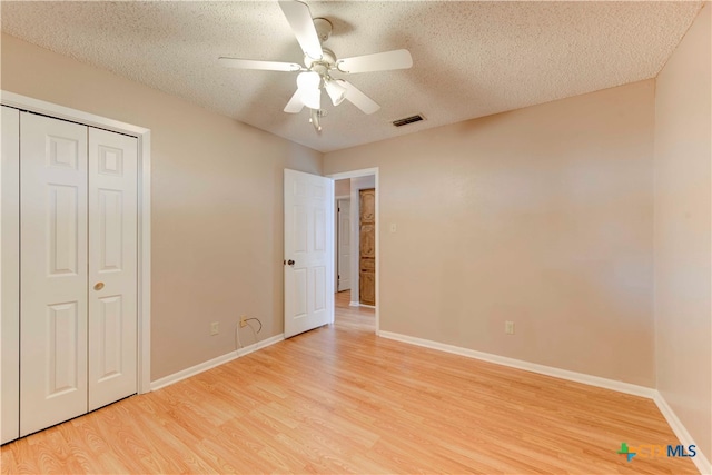 unfurnished bedroom with light hardwood / wood-style floors, ceiling fan, a textured ceiling, and a closet