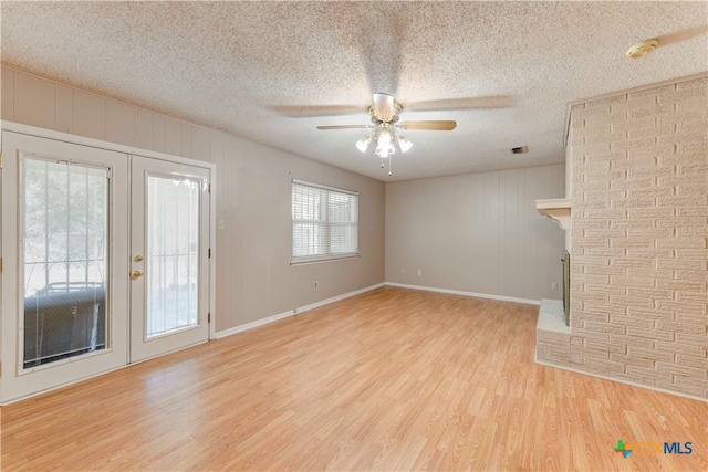 unfurnished living room featuring light hardwood / wood-style floors, ceiling fan, and a textured ceiling