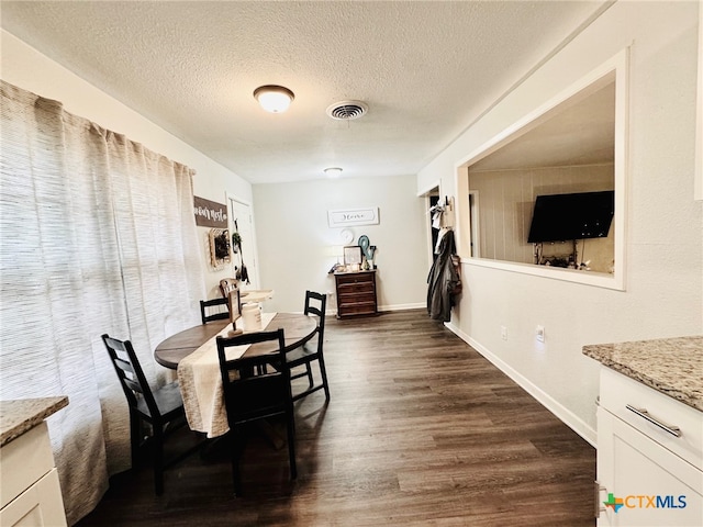 dining room with a textured ceiling and dark hardwood / wood-style floors