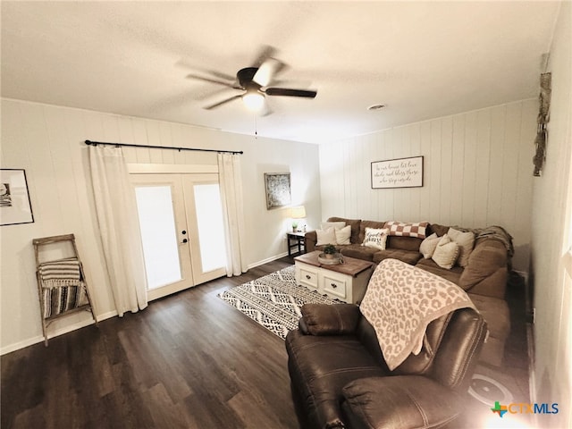 living room featuring wood walls, french doors, ceiling fan, and dark wood-type flooring