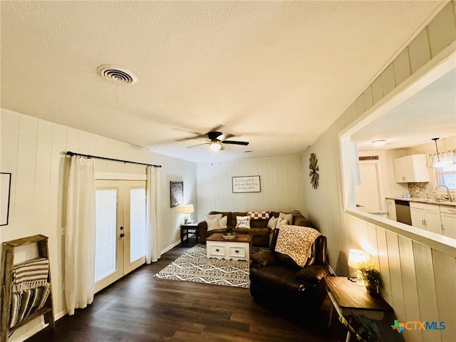 living room featuring ceiling fan, french doors, sink, dark hardwood / wood-style floors, and wooden walls