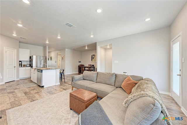 living room with light hardwood / wood-style floors and sink