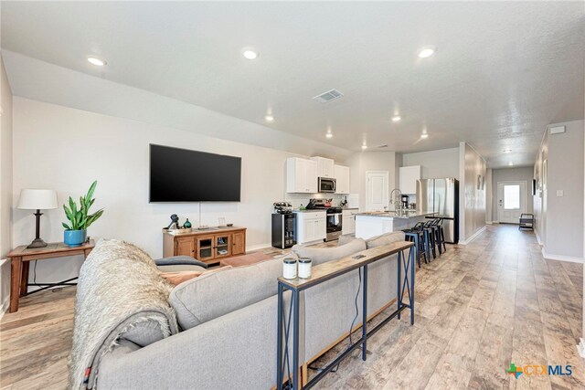 living room with light hardwood / wood-style flooring and sink