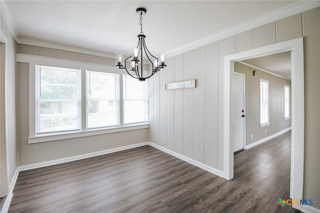 unfurnished dining area with baseboards, a chandelier, dark wood finished floors, and crown molding