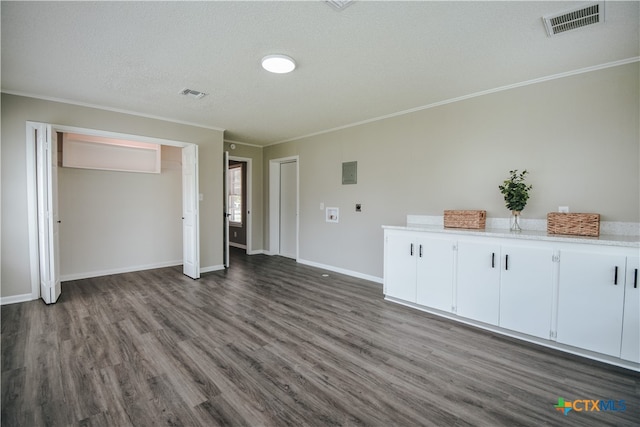 interior space featuring baseboards, dark wood-type flooring, visible vents, and crown molding