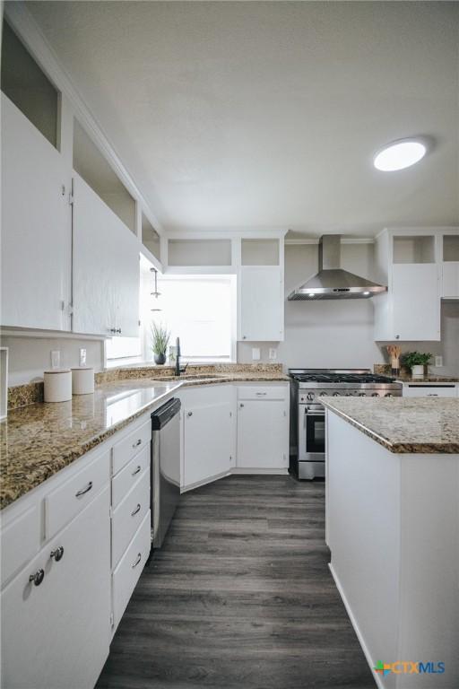 kitchen with open shelves, stainless steel appliances, white cabinets, a sink, and wall chimney range hood