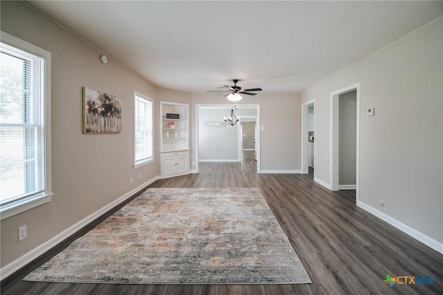 unfurnished living room featuring dark wood-style floors, baseboards, and ceiling fan with notable chandelier