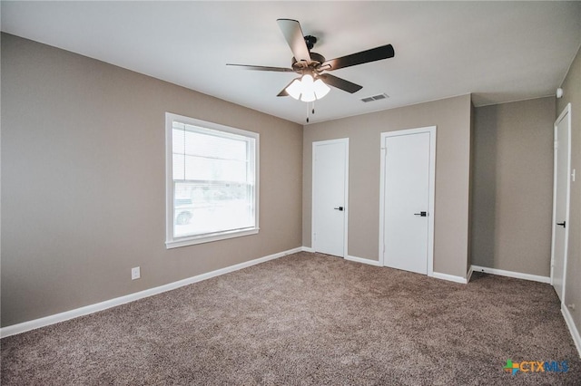 unfurnished bedroom with a ceiling fan, carpet flooring, visible vents, and baseboards