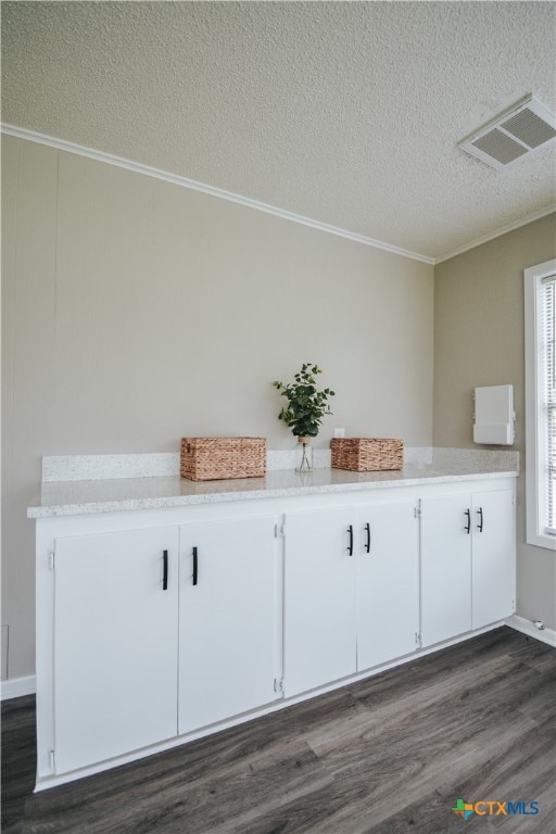 interior space featuring crown molding, a textured ceiling, visible vents, and wood finished floors