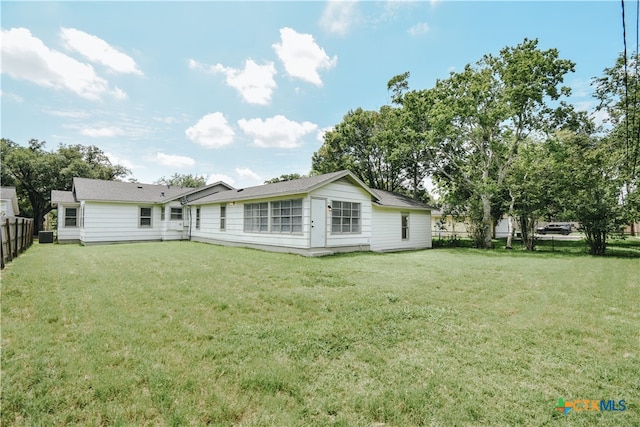 rear view of house with a fenced backyard and a yard