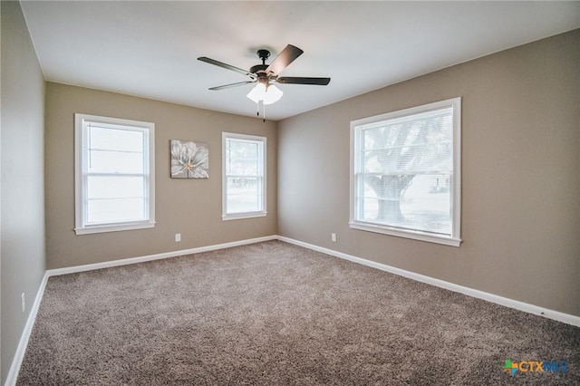 carpeted spare room featuring baseboards and a ceiling fan