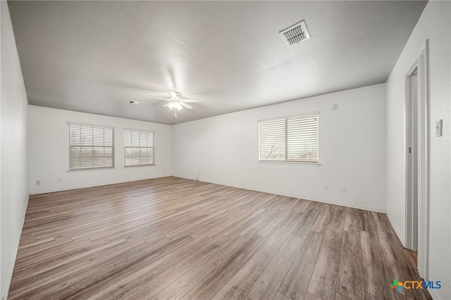 empty room with a textured ceiling, ceiling fan, and light hardwood / wood-style flooring