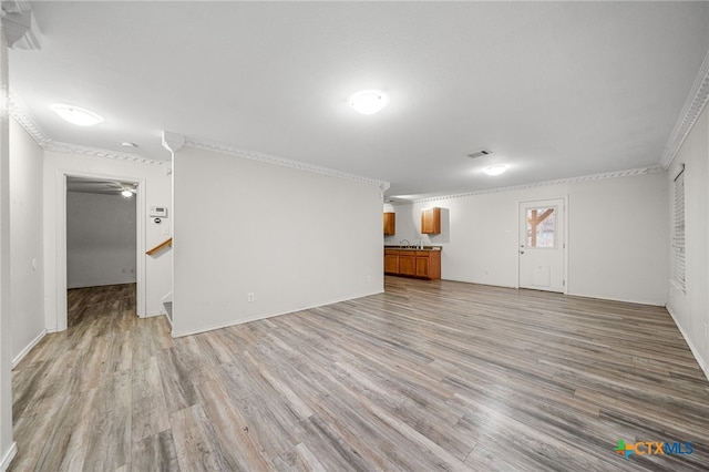 unfurnished living room with crown molding and light hardwood / wood-style floors