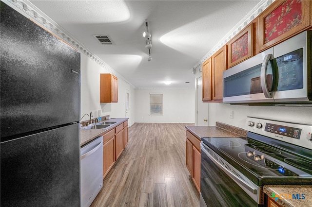 kitchen featuring track lighting, appliances with stainless steel finishes, sink, and light wood-type flooring