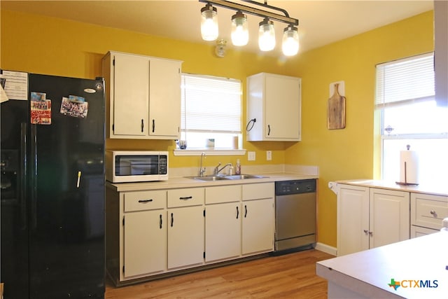 kitchen with black fridge, sink, decorative light fixtures, stainless steel dishwasher, and white cabinets