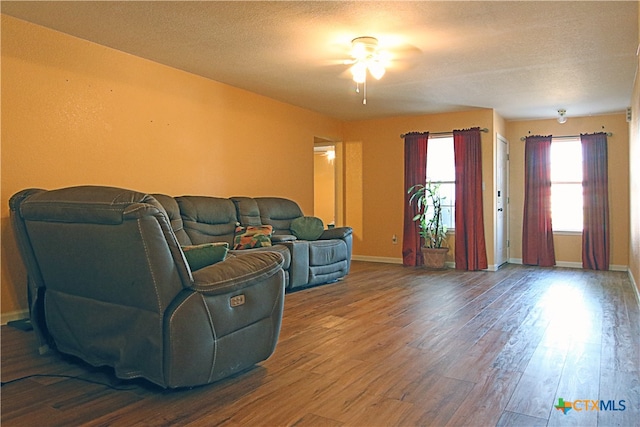 living room featuring hardwood / wood-style floors, ceiling fan, and a textured ceiling