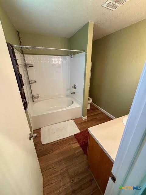 4306 Menard Dr, Killeen, TX 76549 - bathroom featuring toilet, wood finished floors, vanity, shower / washtub combination, and baseboards