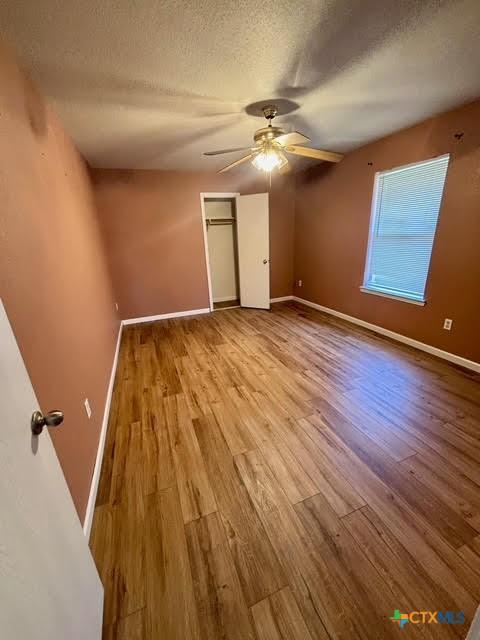 4306 Menard Dr, Killeen, TX 76549 - unfurnished bedroom featuring wood finished floors, baseboards, a textured ceiling, a ceiling fan, and a closet