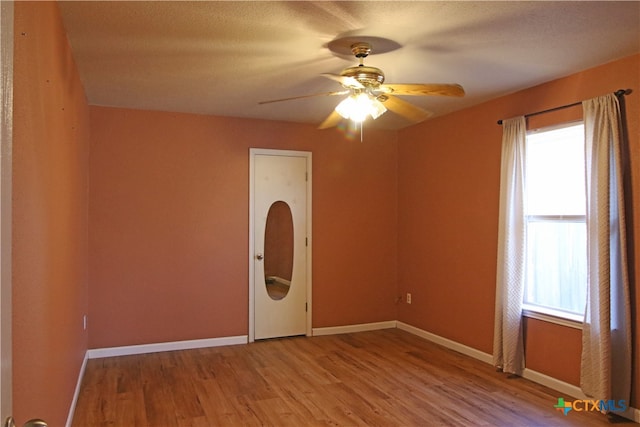 spare room featuring a wealth of natural light, ceiling fan, a textured ceiling, and light wood-type flooring