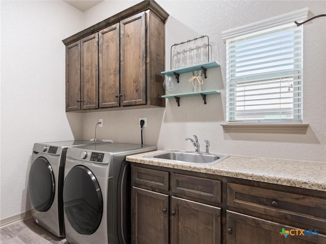 washroom with light hardwood / wood-style flooring, independent washer and dryer, sink, and cabinets