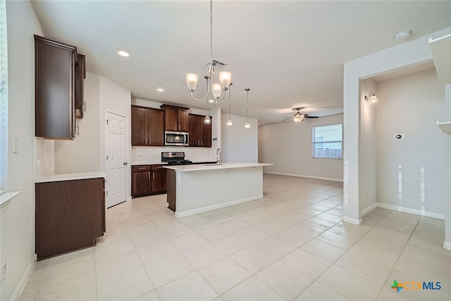 kitchen featuring ceiling fan with notable chandelier, pendant lighting, a kitchen island with sink, dark brown cabinets, and appliances with stainless steel finishes