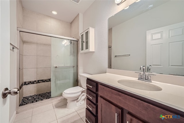 bathroom featuring toilet, vanity, tile patterned flooring, and a shower with shower door