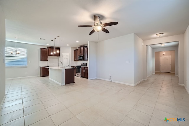 kitchen featuring ceiling fan with notable chandelier, stainless steel appliances, a center island with sink, hanging light fixtures, and sink