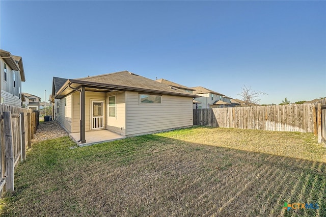 back of property featuring central AC, a patio area, and a yard