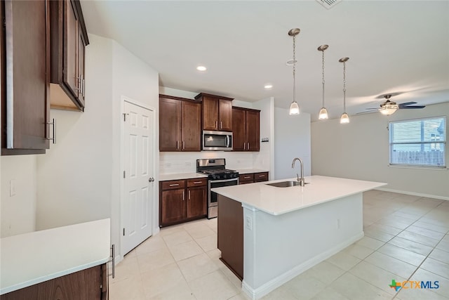 kitchen with stainless steel appliances, hanging light fixtures, sink, light tile patterned floors, and an island with sink