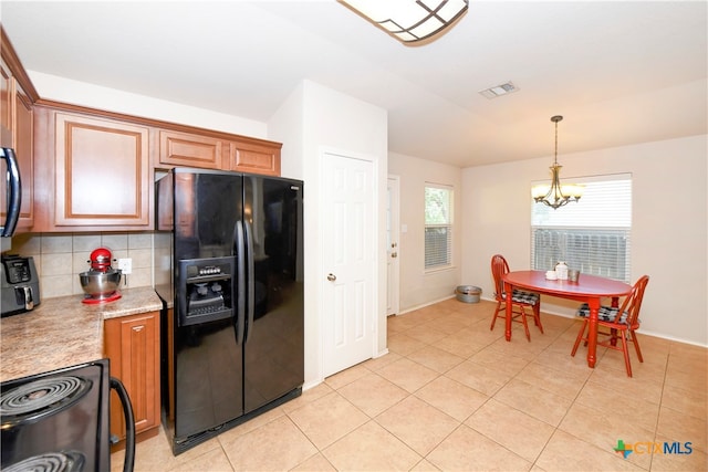 kitchen featuring black fridge, hanging light fixtures, a notable chandelier, stove, and decorative backsplash