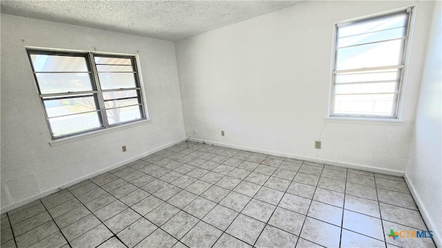 spare room featuring a textured ceiling and baseboards