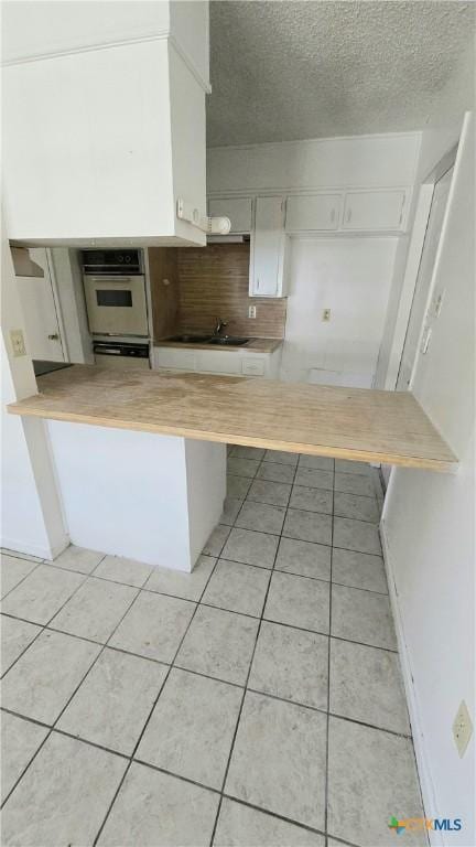 kitchen featuring white cabinetry, white oven, light countertops, and light tile patterned floors