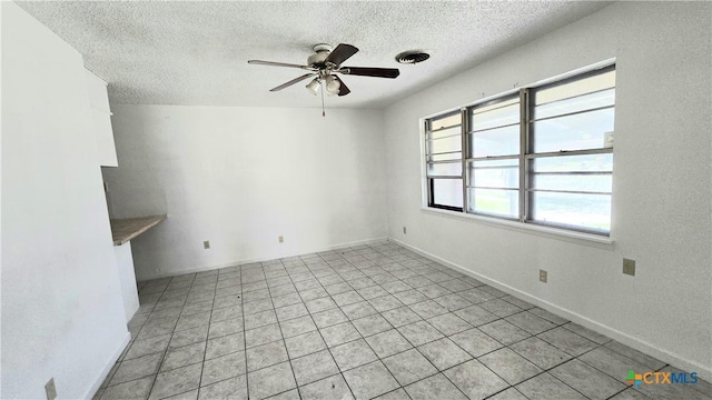 empty room with ceiling fan, a textured ceiling, visible vents, and baseboards