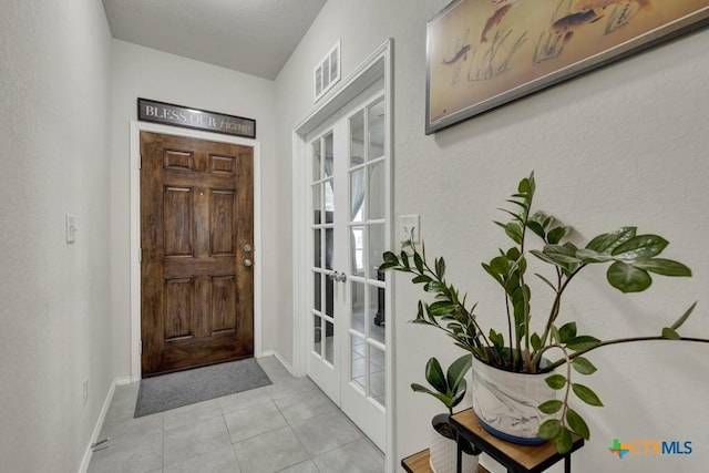 tiled foyer with french doors and baseboards